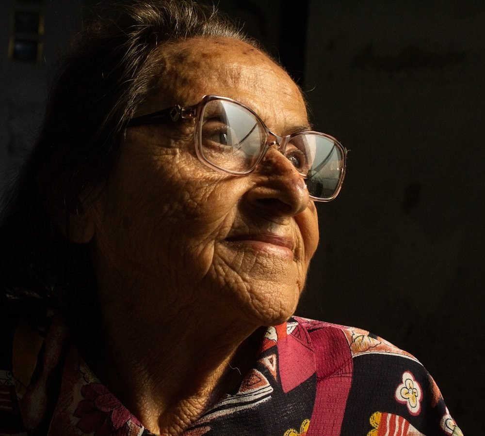Senhora de óculos, sorrindo, olhando para a luz